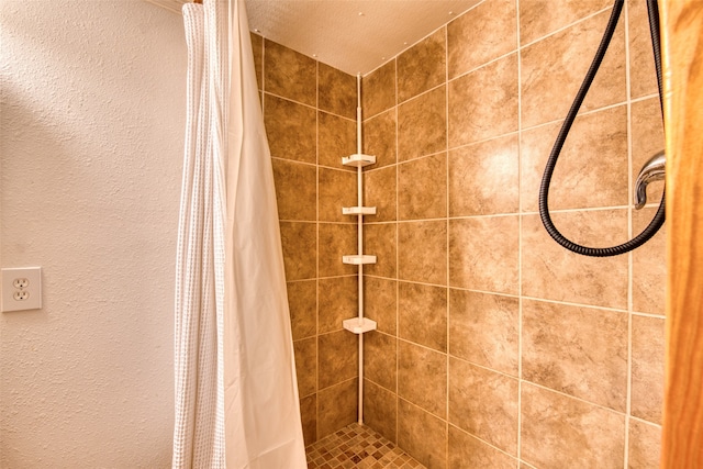 full bathroom featuring a textured wall and tiled shower