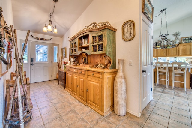 entryway with light tile patterned flooring, an inviting chandelier, and lofted ceiling