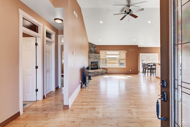 entrance foyer featuring a textured ceiling, light hardwood / wood-style flooring, ceiling fan, and a stone fireplace