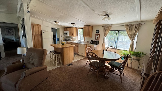 dining room with vaulted ceiling, a textured ceiling, visible vents, and light colored carpet