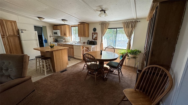 dining area with visible vents, vaulted ceiling, a textured ceiling, and light colored carpet