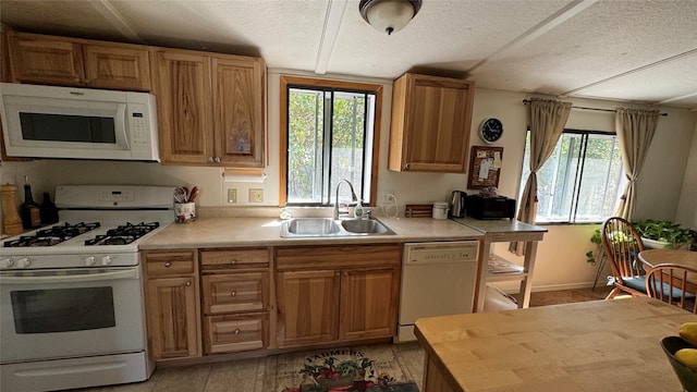 kitchen featuring white appliances, sink, and a textured ceiling