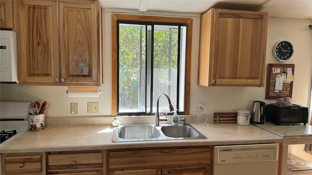 kitchen with light countertops, white appliances, and a sink