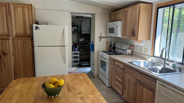 kitchen featuring lofted ceiling, white appliances, wooden counters, and a sink