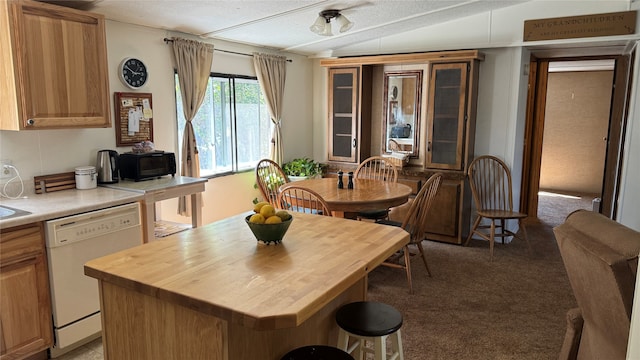 kitchen featuring dark carpet, white dishwasher, a center island, lofted ceiling, and wooden counters