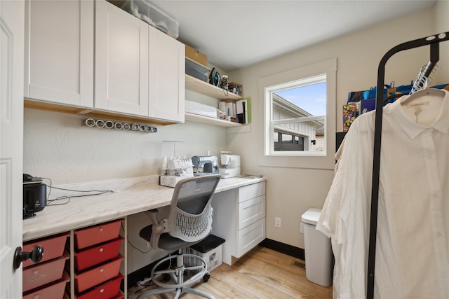 home office featuring light hardwood / wood-style floors and built in desk