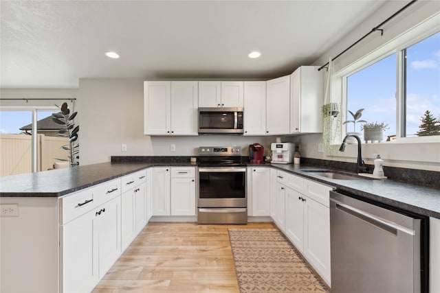 kitchen featuring light wood-type flooring, appliances with stainless steel finishes, sink, and white cabinetry