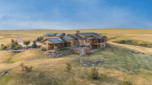 view of front of house featuring stone siding, a standing seam roof, a rural view, and metal roof