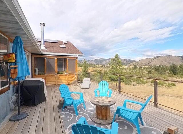 wooden deck featuring a grill, a mountain view, and an outdoor fire pit