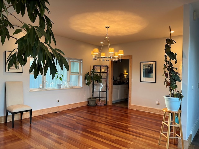 dining room featuring a chandelier, baseboards, and wood finished floors