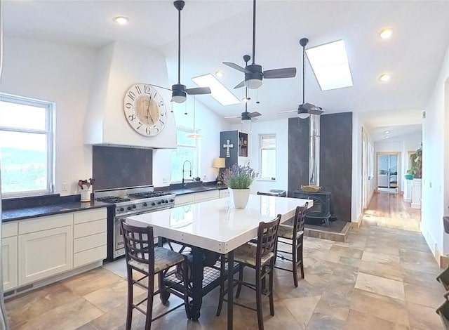 5355 Peaks View Dr, Helena, MT 59602 - kitchen with stainless steel gas range oven, a wood stove, a ceiling fan, vaulted ceiling, and dark countertops