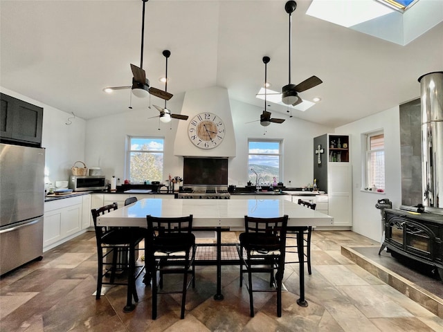 kitchen featuring stainless steel appliances, white cabinetry, a wood stove, and a kitchen breakfast bar