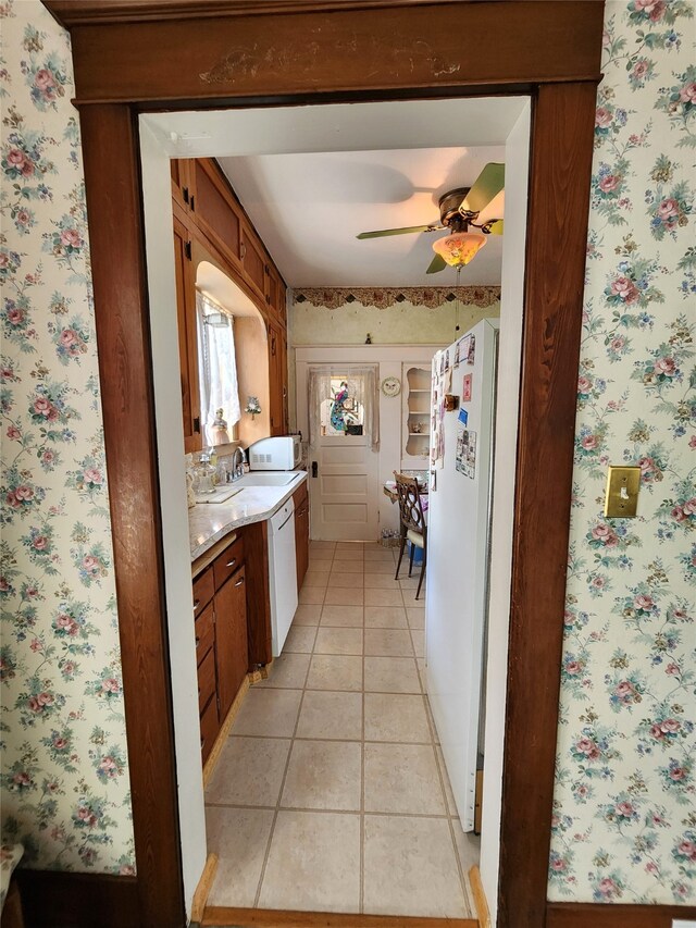 kitchen with sink, white appliances, ceiling fan, and light tile patterned flooring