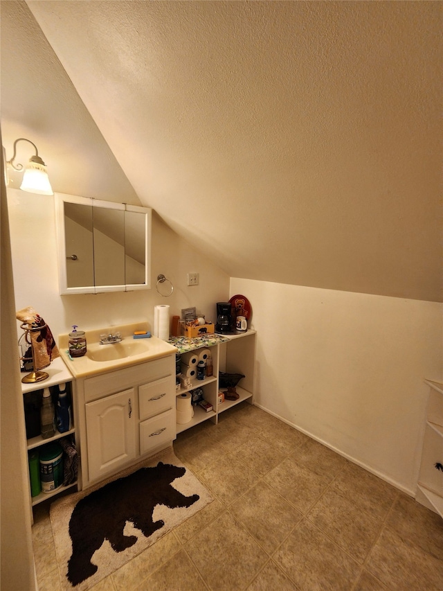 bathroom featuring vanity, a textured ceiling, and vaulted ceiling