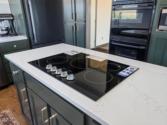 kitchen with tile patterned flooring, light stone countertops, black electric cooktop, and stainless steel refrigerator