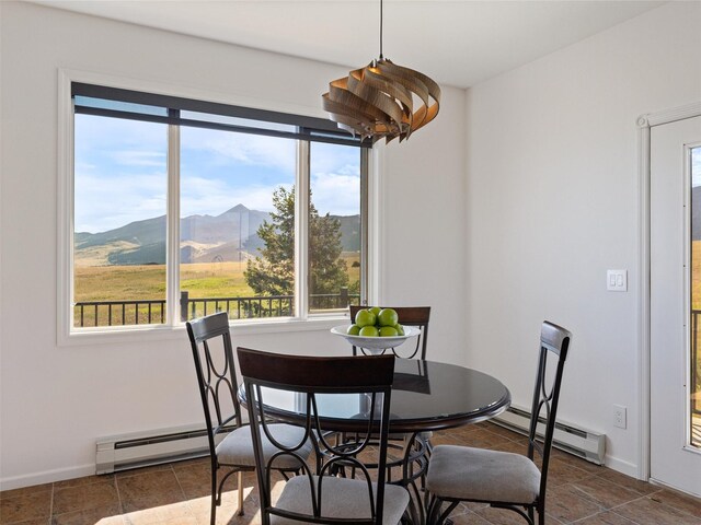 dining space with dark tile patterned flooring, baseboard heating, and a mountain view