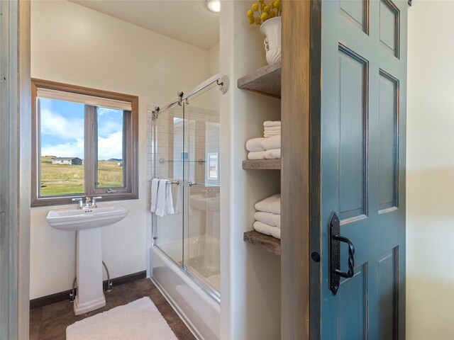 bathroom with tile patterned flooring, bath / shower combo with glass door, and sink