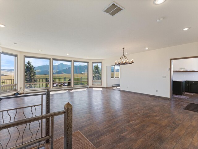 unfurnished living room with a baseboard radiator, a mountain view, a notable chandelier, and dark hardwood / wood-style flooring