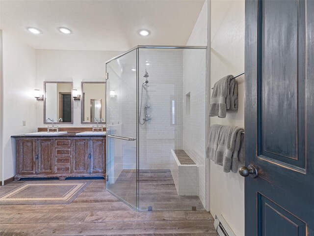 bathroom featuring hardwood / wood-style flooring, an enclosed shower, baseboard heating, and vanity