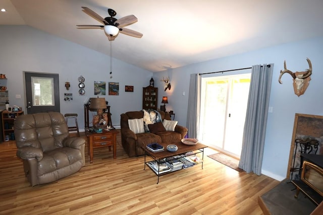 living room with a wood stove, light wood finished floors, vaulted ceiling, and a ceiling fan