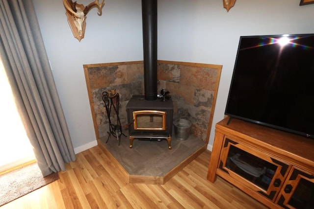 interior details featuring a wood stove, baseboards, and wood finished floors