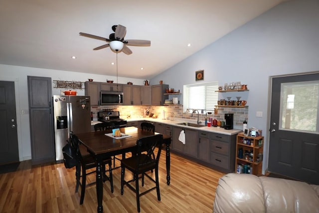 kitchen with appliances with stainless steel finishes, a sink, light wood finished floors, and open shelves