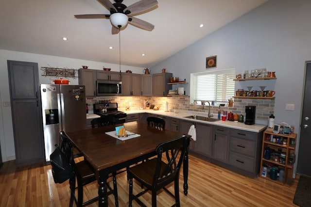 kitchen featuring open shelves, light countertops, appliances with stainless steel finishes, a sink, and light wood-type flooring