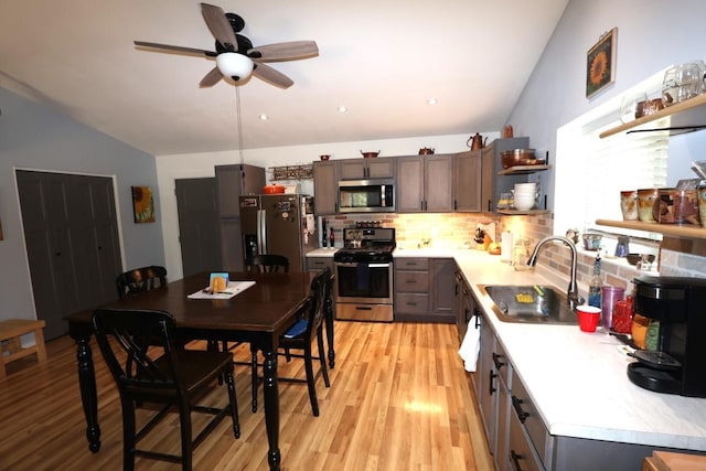 kitchen with open shelves, appliances with stainless steel finishes, a sink, and light countertops