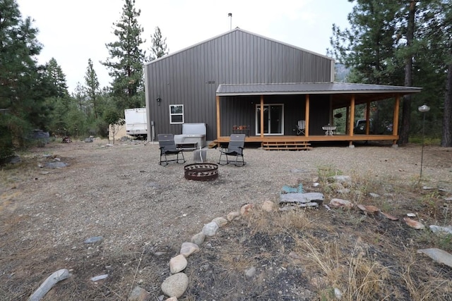 back of property featuring an outdoor fire pit and metal roof