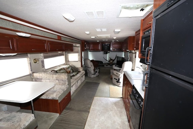 kitchen with black appliances, visible vents, a wealth of natural light, and a textured ceiling