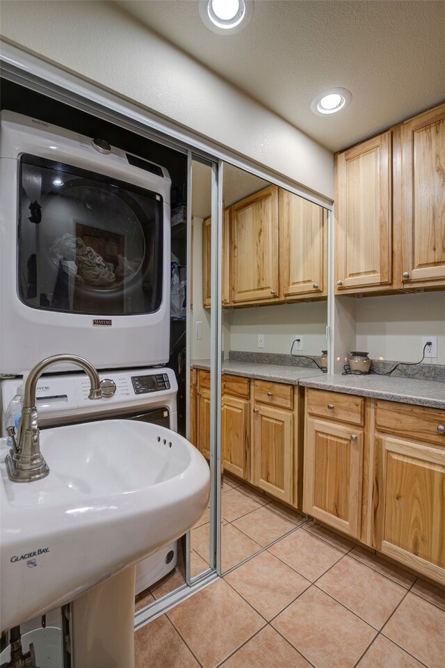 interior space featuring a textured ceiling, sink, light tile patterned flooring, and stacked washer / drying machine