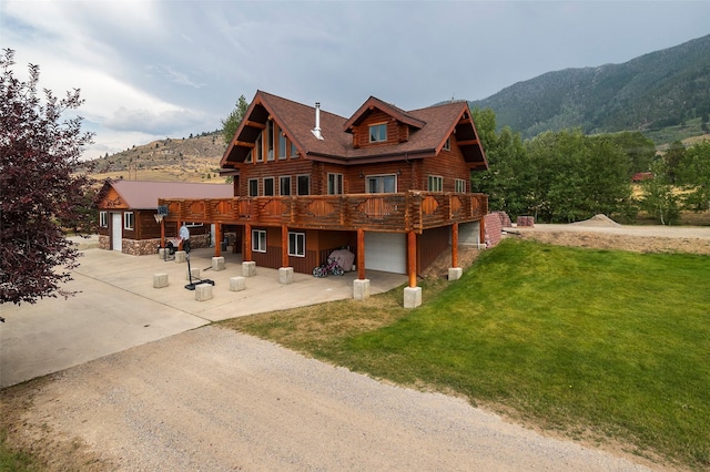 4930 Saddle Rock Rd, Butte, MT 59701 - rear view of property with a yard, an attached garage, log siding, a deck with mountain view, and driveway