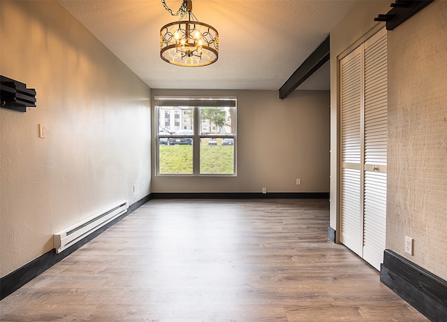 empty room with baseboard heating, a chandelier, wood-type flooring, a textured ceiling, and beamed ceiling