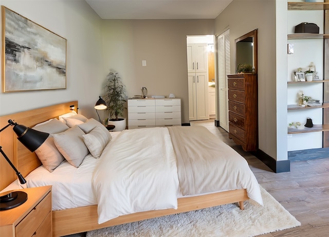 bedroom featuring a closet, connected bathroom, and light wood-type flooring