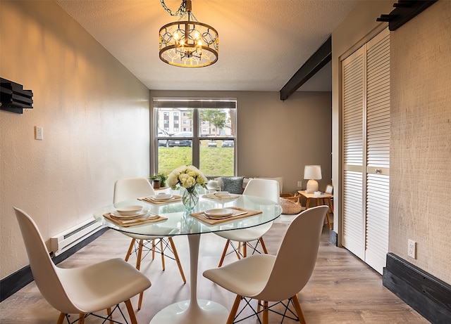 dining space featuring hardwood / wood-style floors, a baseboard heating unit, an inviting chandelier, and a textured ceiling