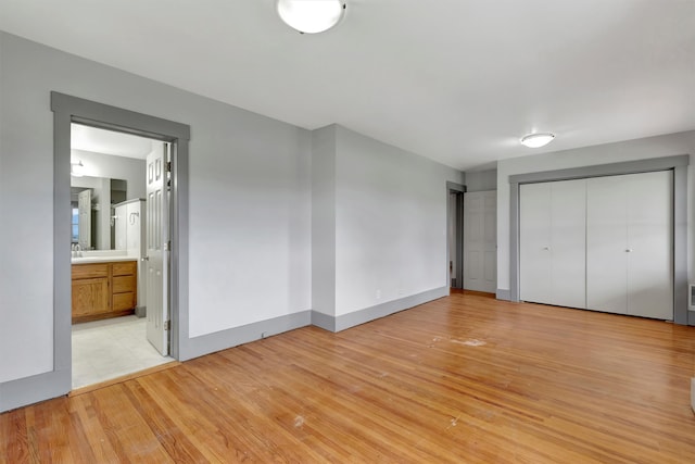 unfurnished bedroom with ensuite bath, sink, and light hardwood / wood-style flooring