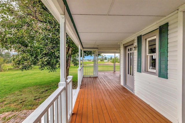 wooden deck featuring a porch and a lawn