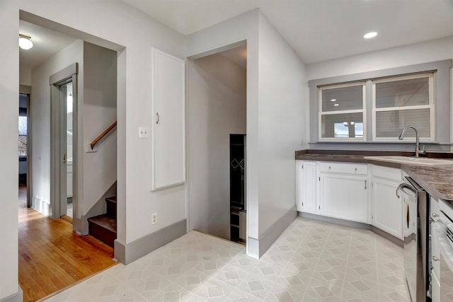 kitchen featuring stainless steel dishwasher, a healthy amount of sunlight, sink, and white cabinets