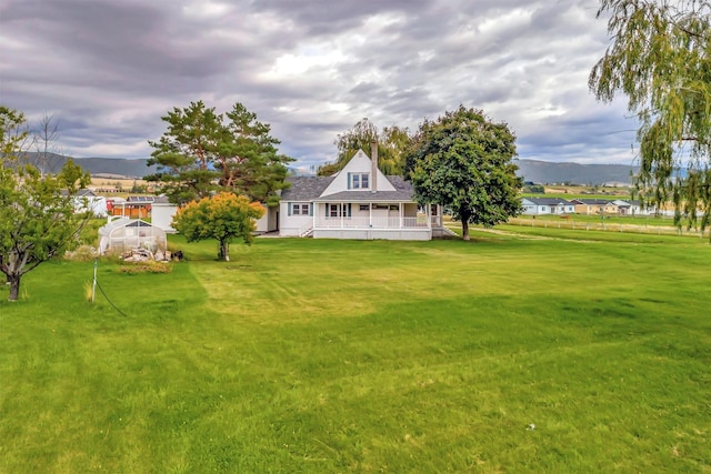 view of yard with a porch, an outdoor structure, and a mountain view