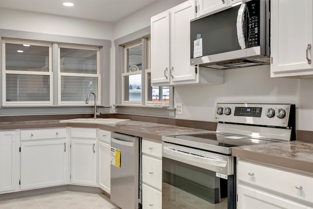 kitchen with white cabinetry, sink, stainless steel appliances, and light stone countertops