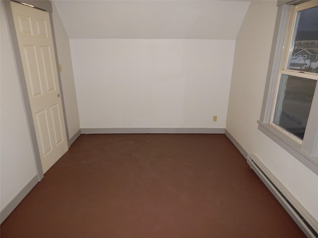 empty room featuring lofted ceiling and a baseboard heating unit