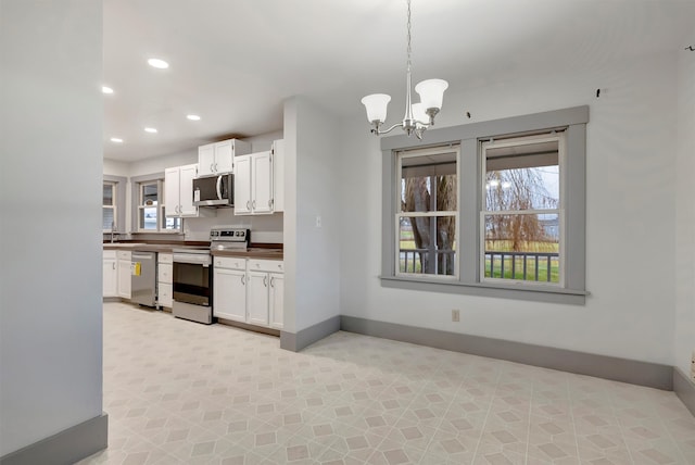 kitchen with hanging light fixtures, white cabinetry, appliances with stainless steel finishes, and a notable chandelier