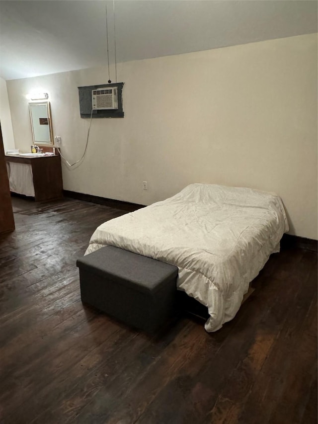 bedroom with dark hardwood / wood-style flooring and an AC wall unit