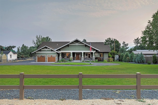 craftsman-style house with driveway, a garage, fence, and a front lawn