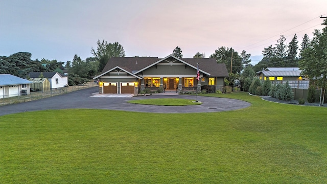 view of front of house featuring driveway, fence, and a lawn