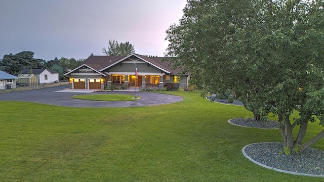 craftsman-style house with driveway, covered porch, a garage, and a yard