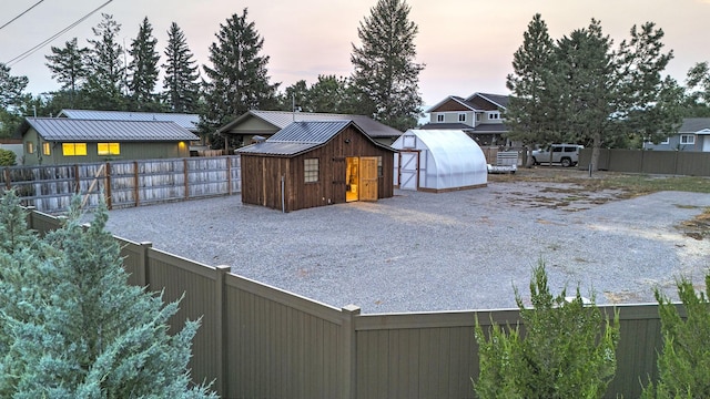 view of yard with a greenhouse, an outdoor structure, and a fenced backyard