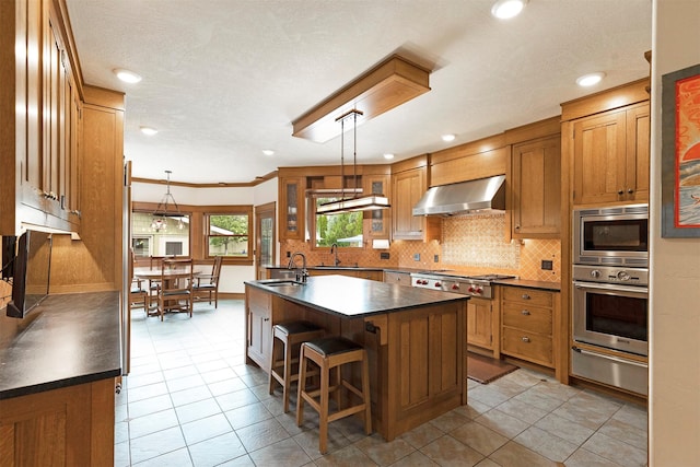 kitchen featuring dark countertops, wall chimney exhaust hood, appliances with stainless steel finishes, backsplash, and a warming drawer