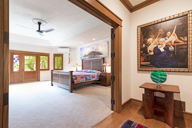 bedroom featuring carpet floors, crown molding, a raised ceiling, a wall mounted air conditioner, and baseboards