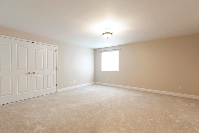 spare room with light colored carpet and baseboards